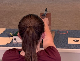 Woman firing a gun at a target with focus and precision