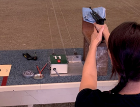 Woman standing on a table, holding a gun with confidence