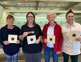Four women holding certificates, celebrating their achievements